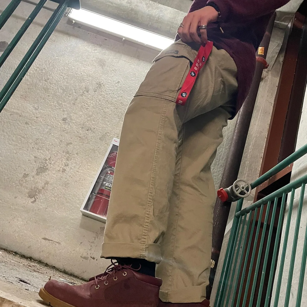 A close view of burgundy boots, cargo trousers and a key strap on a stairway