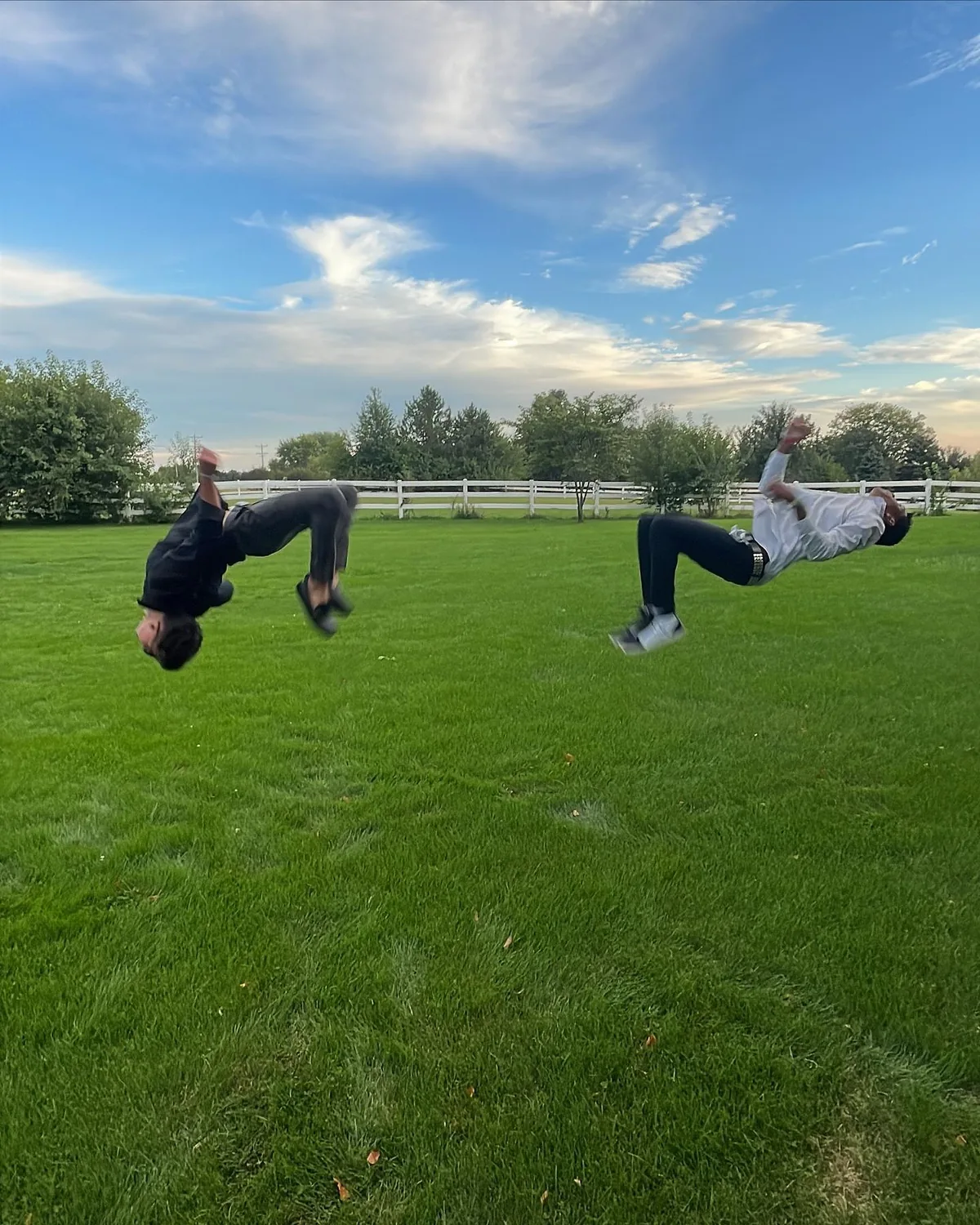 Two people mid-flip on a lawn