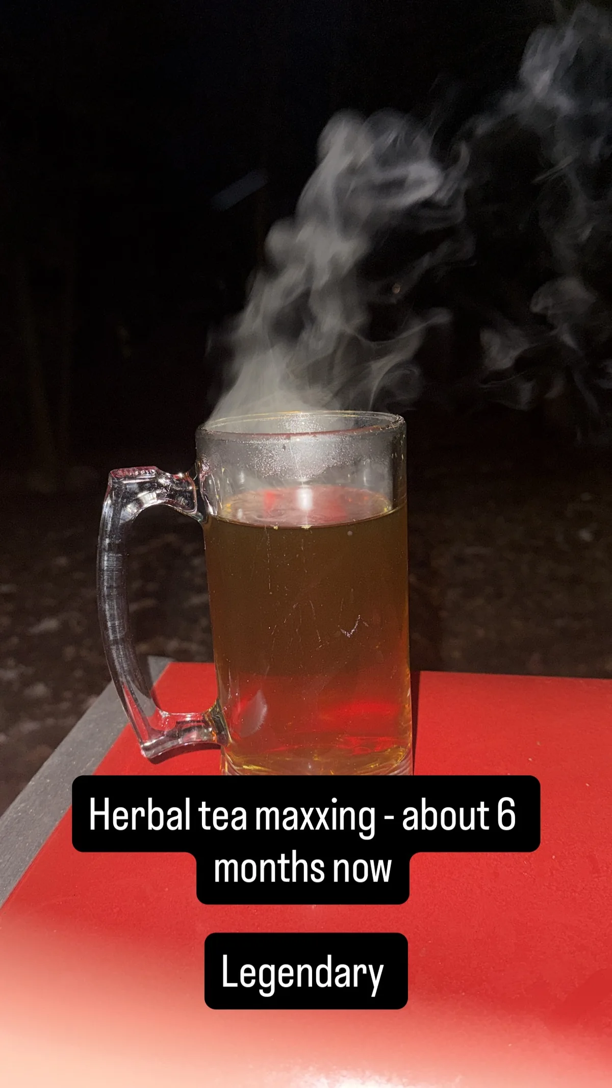 Steam rising from a glass mug outside at night
