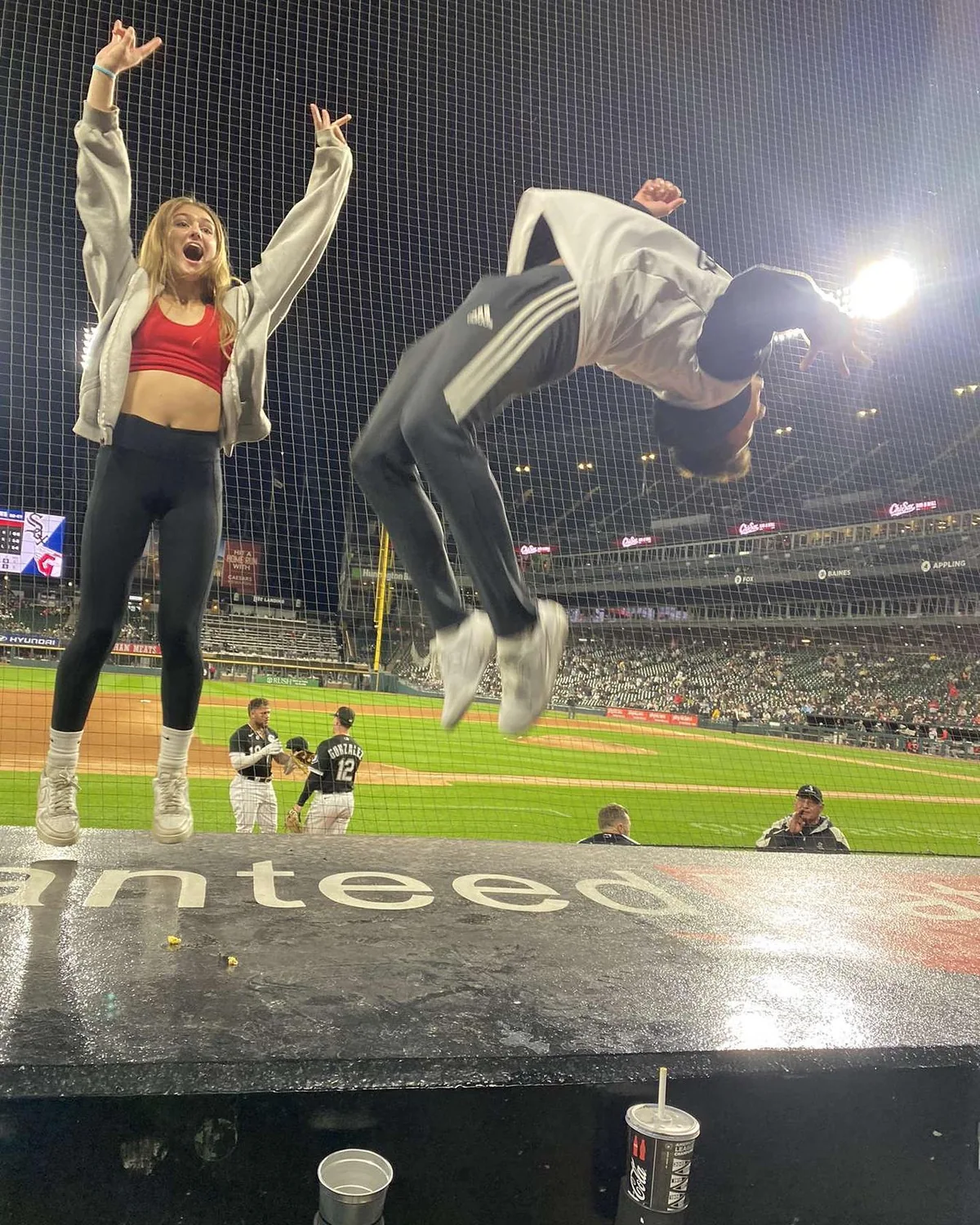 A flip beside a friend at a baseball stadium