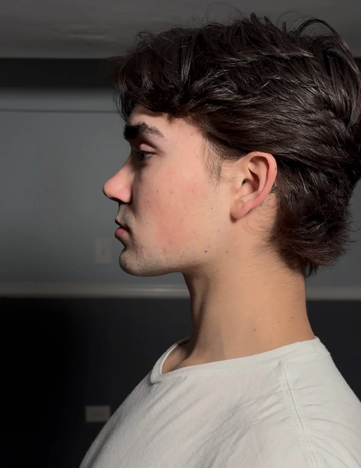 Alex in profile against a plain wall