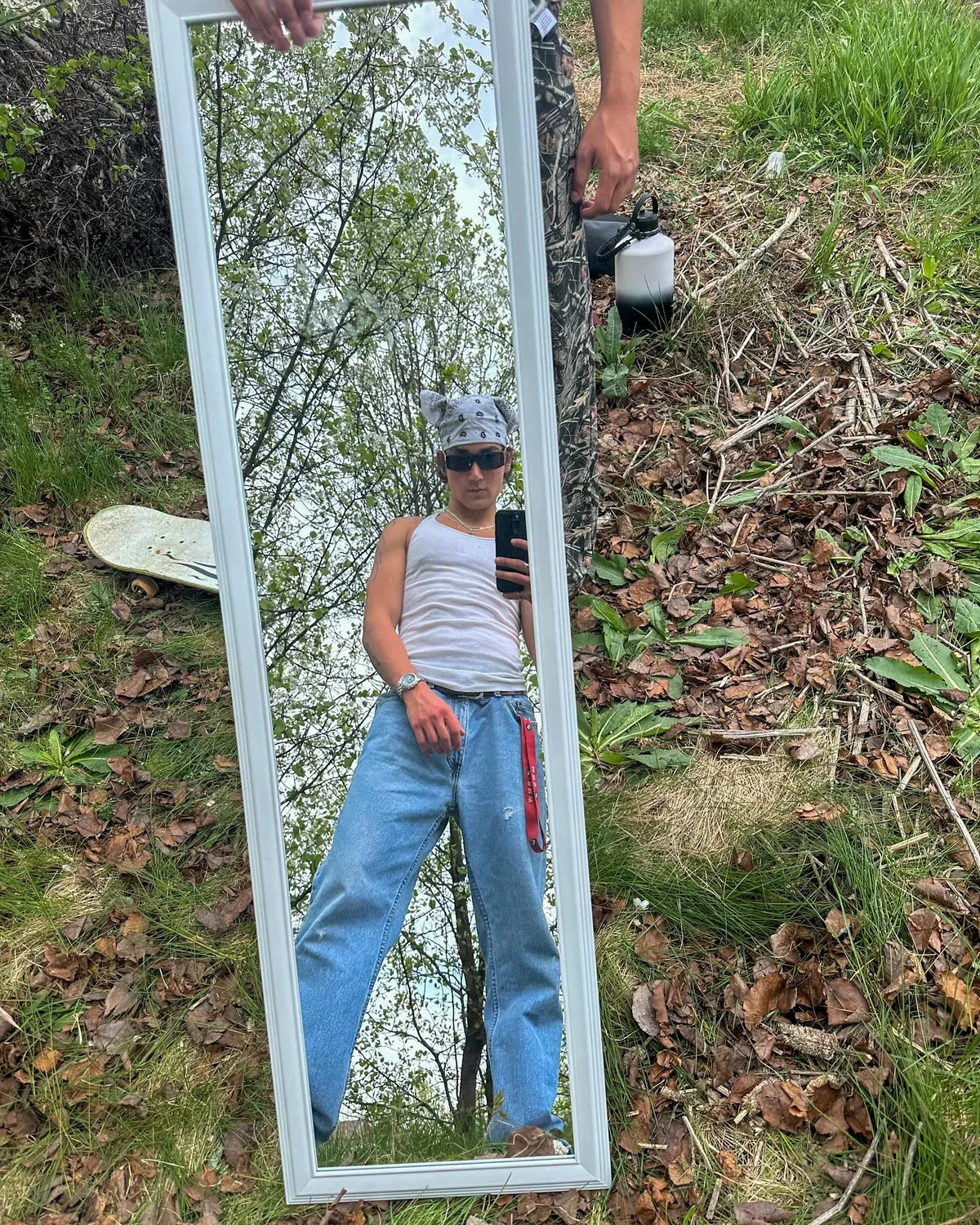 A mirror on the grass reflecting Alex and the trees