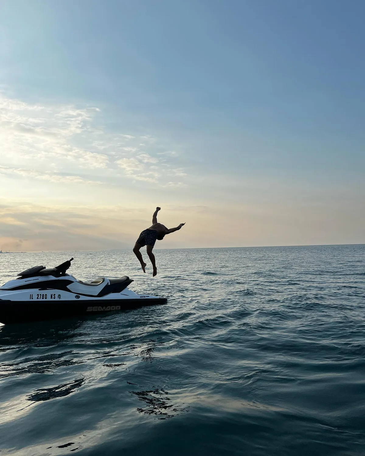 A leap above water beside a personal watercraft