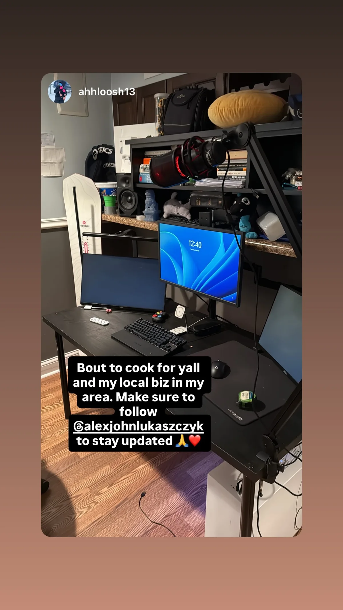 Desk with two monitors, a microphone, books and a snowboard beside it